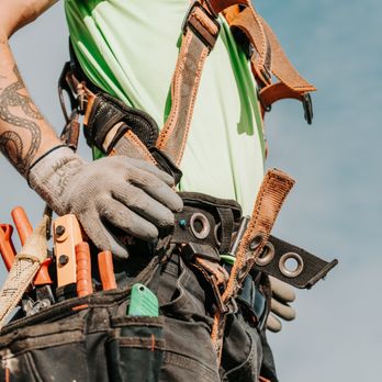 Moss Boss Roofing - Roofing professional wearing a safety harness and tool belt while working on a residential roof. - Roofing Near Me Moss Boss Roofing - Roofing professional wearing a safety harness and tool belt while working on a residential roof. - Roofing Near Me