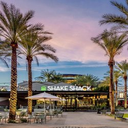 Shake Shack and outdoor seating framed by illuminated palm trees at dusk at Kierland Commons.