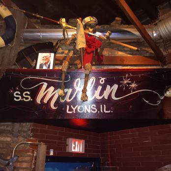 Marlins Bar & Grill - the sign for the restaurant - A decorative skeleton figure is positioned above a sign for s.s. Maulin in Lyons, Illinois, inside a restaurant or bar with brick walls and exposed ductwork. - Bars Near Me - Lyons, Illinois