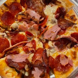 Deep Pan Meat Lovers Pizza - A pizza topped with pepperoni, bacon, ham, and mushrooms, served on a metal tray with a checkered tablecloth.