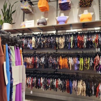 Lululemon - The image shows a retail store display with multiple racks of women's underwear in various colors and styles. Mannequins on a shelf above the racks are dressed in sports bras and tank tops. A potted plant is also visible on the left side of the display. The store appears well-organized with a focus on intimate apparel. - Sports Wear Near Me - Rosemont, Illinois