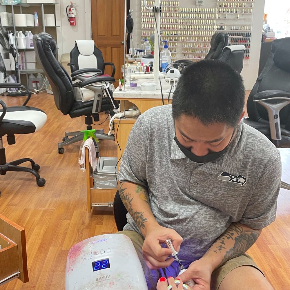 Nail tech doing his thing, with second color wall in background. Nail tech doing his thing, with second color wall in background.