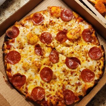 The Kitchen + Bar - A pepperoni and cheese pizza in a cardboard delivery box on a granite countertop, with a side of fried chicken and a small drink nearby. - Bars Near Me - Santa Fe, New Mexico