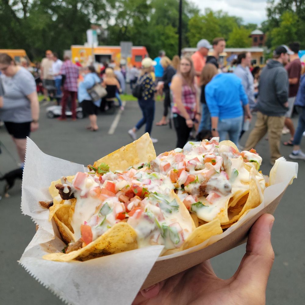 a person holding a plate of nachos a person holding a plate of nachos
