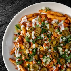 Fuego Cravings - Fried seasoned fries piled high with rich nacho cheese, your choice of meat, spicy jalapeños, guacamole sauce, sour cream, cilantro/onion.
