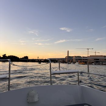 SeaDC - A photo taken from a boat on the Potomac River at sunset, showing the water, city skyline, and cranes in the distance. - Boat Charters Near Me - Washington, DC, District of Columbia