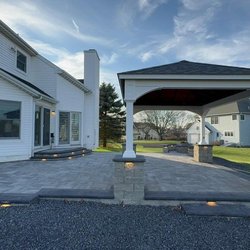 Penn Home Remodeling - A large black heavy-duty tow truck is hooked up to a white dump truck, parked on a gravel lot in front of a corrugated metal ...