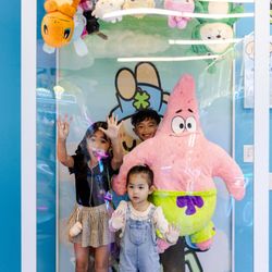 Kids taking photos in the upside down claw machine photo op