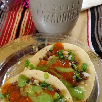 Rain on 4th - a plate of tacos and a cup of coffee - A tequila mug with a salted rim and a blue top, alongside two tacos filled with meat, vegetables, salsa, and cilantro. - Gay Bars Near Me - Austin, Texas