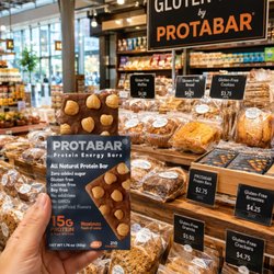 My PROTABAR beside a display of gluten-free baked goods and packaged snacks inside the market.