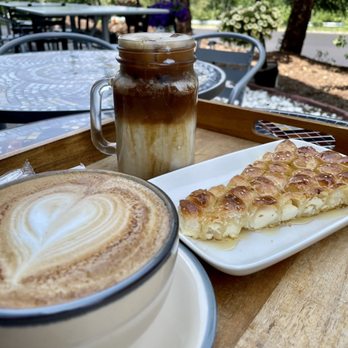 Qamaria Coffee - Cappuccino, iced Qamaria latte with oat milk, and honeycomb bread - all enjoyed while seated in Qamaria's outdoor seating area. - Coffee & Tea Near Me - Commerce Township, Michigan