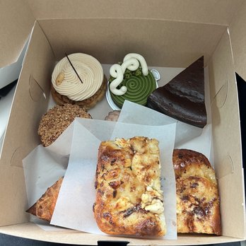 T55 Patisserie - Clockwise: matcha tart, basque cheesecake, black truffle and goat cheese focaccia, crab scone, raspberry financier, banoffee choux - Desserts Near Me - Bothell, Washington