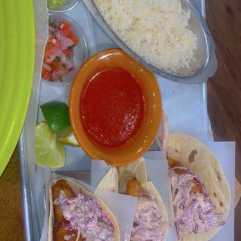 Los Cabos - Fish Tacos - Three fish tacos topped with coleslaw, served with a bowl of red sauce, rice, lettuce, pico de gallo, and lime wedges on a metal tray. - Seafood Near Me - Akron, Ohio