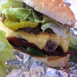 Bacon cheeseburger with lettuce, pickles, green peppers and hot sauce