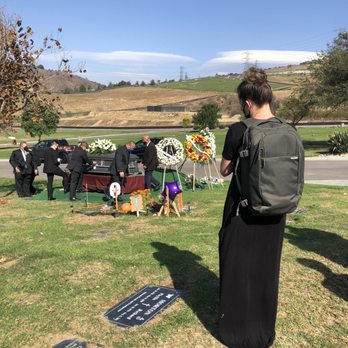 Shore and Wave - Stephanie (Shore and Wave) capturing video of the pallbearers carrying the casket to the burial site. - Videographers Near Me Shore and Wave - Stephanie (Shore and Wave) capturing video of the pallbearers carrying the casket to the burial site. - Videographers Near Me