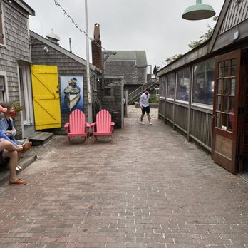 Slip 14 - a man sitting on a bench in a street - Bars Near Me - Nantucket, Massachusetts
