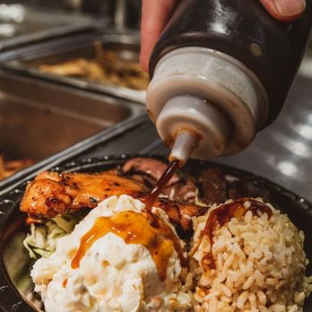 Mo' Bettahs Hawaiian Style Food -  a person pouring ketchup on a plate of food - Hawaiian Near Me - Ammon, Idaho