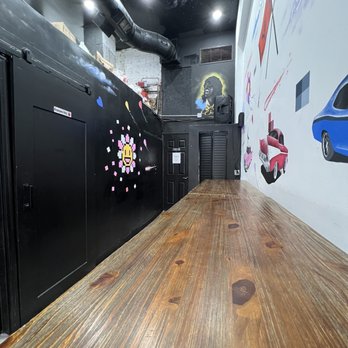 Simply Fried - a long hallway with black doors and a mural on the wall - Fish & Chips Near Me - Queens, New York