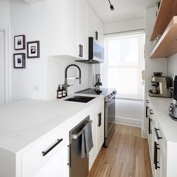 Apex Remodeling - a kitchen with white cabinets and wood floors - General Contractors Near Me