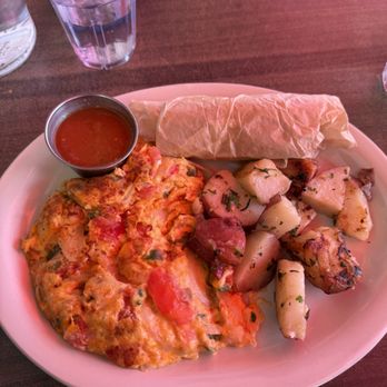 Millie's Cafe - Pasadena - Vegan Huevos a la Mexicana with regular potatoes - A breakfast plate includes an omelette with vegetables, roasted potatoes with herbs, and a breakfast burrito, accompanied by a small cup of salsa. - Breakfast & Brunch Near Me - Pasadena, California