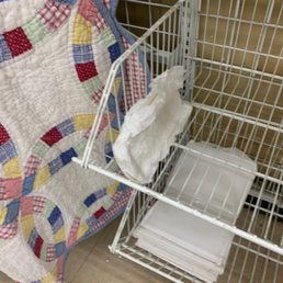 DIAPER - A wire shopping cart contains a crumpled tissue and a stack of paper towels, positioned next to a colorful quilt.