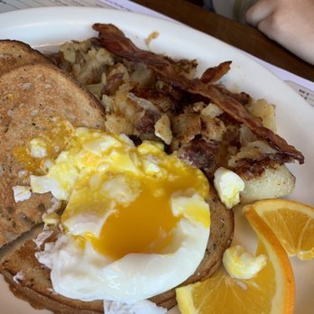 Union Cafe - Poached eggs breakfast - A breakfast plate features poached eggs on toast, crispy bacon, roasted potatoes, and orange slices, served on a white plate. - Diners Near Me - Schenectady, New York