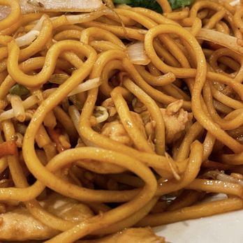 Dim Sum Kitchen - A detailed close-up of stir-fried noodles with bean sprouts, onions, and pieces of chicken, garnished with some greens. - Dim Sum Near Me - Bradenton, Florida