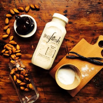 Refresh Juice - a bottle of almond milk, a bowl of almonds, and a cutting board on a wooden table - Juice Bars & Smoothies Near Me - Guelph, Ontario Refresh Juice - a bottle of almond milk, a bowl of almonds, and a cutting board on a wooden table - Juice Bars & Smoothies Near Me - Guelph, Ontario