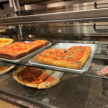 Upside Pizza - a variety of pizzas in a display case - Pizza Near Me - New York, New York