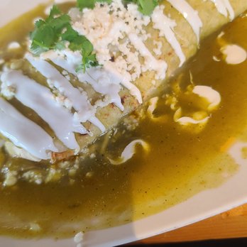 Bread+Salt - Pork Burrito - A burrito garnished with cilantro, cheese, and drizzled with white sauce, served on a white plate with green sauce around it. - Breakfast & Brunch Near Me - Frisco, Colorado