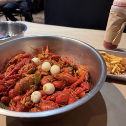 Crawfish with tom yum seasoning and quail eggs Fries and hush puppies in the background. Crawfish with tom yum seasoning and quail eggs Fries and hush puppies in the background.