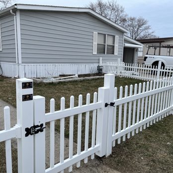Remodeling Gamino 100% - a white picketed fence in front of a house - Siding Near Me Remodeling Gamino 100% - a white picketed fence in front of a house - Siding Near Me