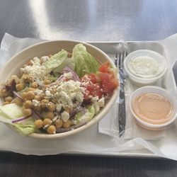 Pita Bowl Greek Cuisine - Brown Rice Bowl, Chicken Souvlaki, Lettuce, Tomato, Cucumber, Red Onion, Chickpeas, Feta Cheese with Tzatziki and Pita Sauce.