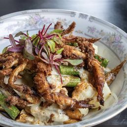 Soft Shell Crab Poutine - A bowl of soft shell crab poutine with fried crab, green beans, cheese curds, and microgreens, served in a floral-patterned dish.