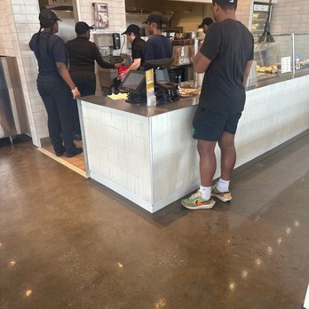 CAVA - a man standing at a counter in a restaurant - Mediterranean Near Me - Baton Rouge, Louisiana CAVA - a man standing at a counter in a restaurant - Mediterranean Near Me - Baton Rouge, Louisiana