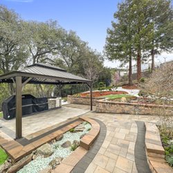 Stones Landscaping - Installation of Catalina Grana pavers with a midnight effect, an outdoor kitchen, a design with white and red lava rocks.