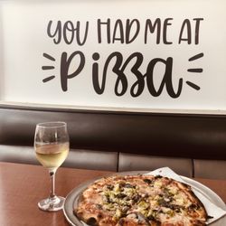 Randy's Wooster Street Pizza - Thin and crispy vegetable pizza with anchovies and a glass of Chardonnay Wine .