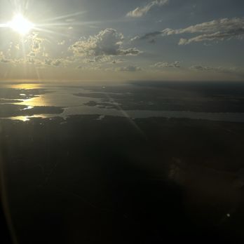 Delta Airlines - Flying to Florida from NY - An aerial photograph shows lakes, land, and clouds with the sun shining brightly in the sky. - Airlines Near Me - Warwick, Rhode Island