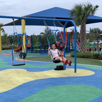 Hillsboro El Rio Park - Double baby swings, with the little kid playground in the background. - Parks Near Me - Boca Raton, Florida