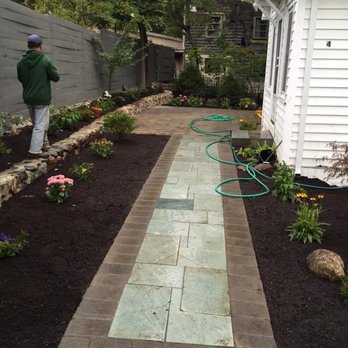 Tony Landscape - a man watering a garden with a hose - Landscaping Near Me