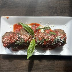 Exquisite Bistro - Mouth watering meatballs sitting on a ricotta cheese base, topped with marinara, fresh basil, & Parmesan cheese.