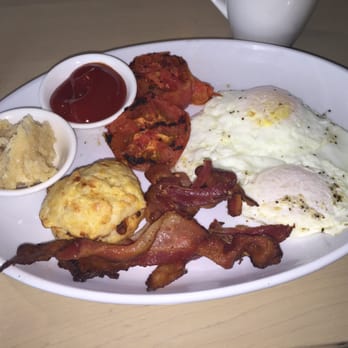 The Hearth - The breakfast consisting of 2 eggs over easy, bacon, tomatoes and a side of ketchup, tiny biscuit and maple butter and coffee $18 - American Near Me - Mississauga, Ontario