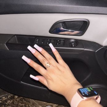 Century Nails - Nails - A hand with long, light pink nails and a ring is placed on the window control panel of a car door, with a smartwatch on the wrist. - Nail Salons Near Me - Phoenix, Arizona