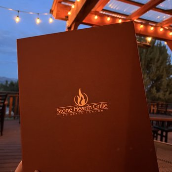 Stone Hearth Grille - a person holding up a menu - American Near Me - Tropic, Utah Stone Hearth Grille - a person holding up a menu - American Near Me - Tropic, Utah