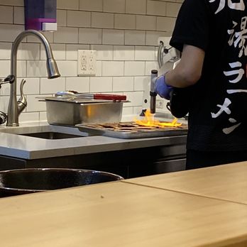 Kyuramen - Flushing - At the bar you can see the chef charring the meat that goes on top of the noodle soups - Ramen Near Me - Flushing, New York Kyuramen - Flushing - At the bar you can see the chef charring the meat that goes on top of the noodle soups - Ramen Near Me - Flushing, New York