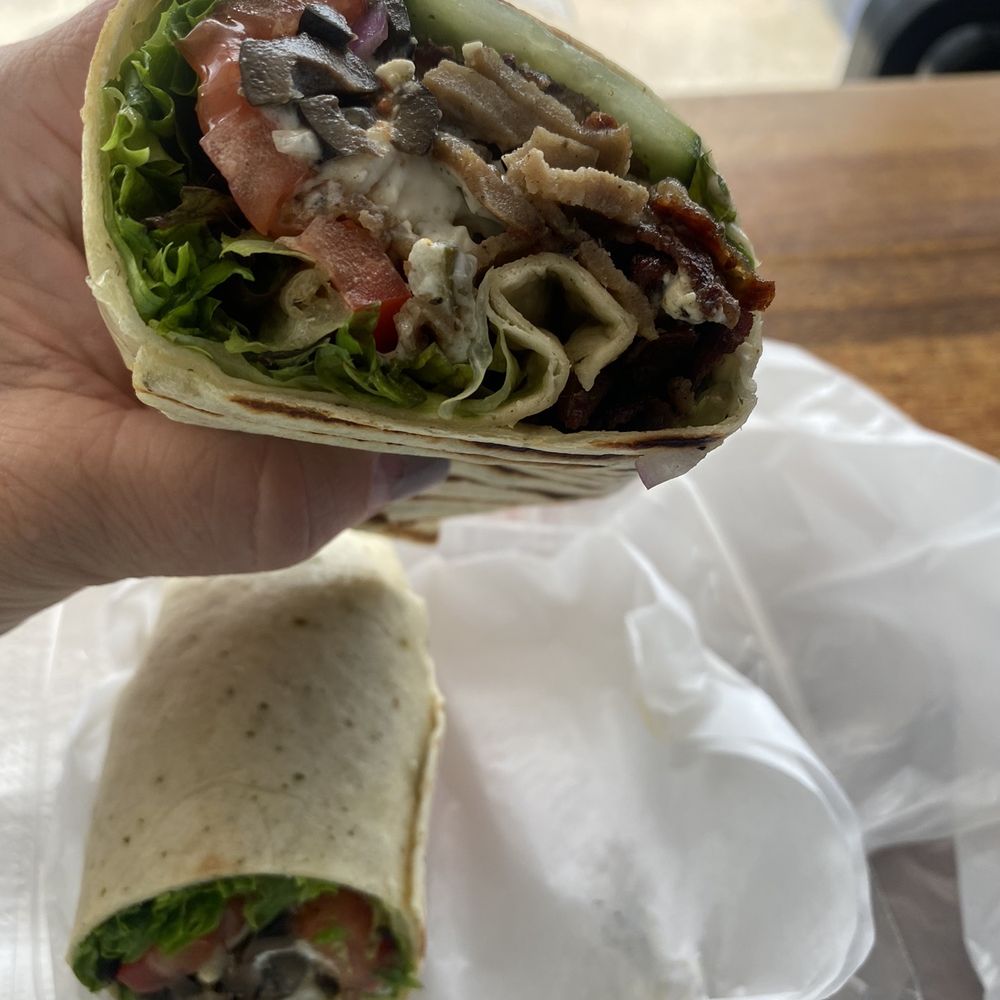 a hand holding a wrap of food a hand holding a wrap of food