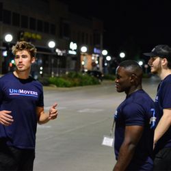 UniMovers Iowa City - A team of young UniMovers employees standing on a downtown street at night, wearing matching branded t-shirts...