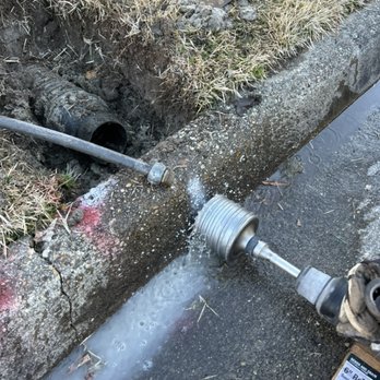 Outdoor Drainage Solutions - Curb drilling a 4 inch hole using the "wet cut" method - Plumbing Near Me - Chesapeake, Virginia Outdoor Drainage Solutions - Curb drilling a 4 inch hole using the "wet cut" method - Plumbing Near Me - Chesapeake, Virginia