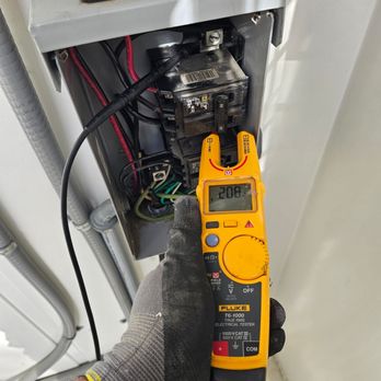 Tarin Electric & Lighting - Electrical voltage testing on a breaker panel using a Fluke multimeter, showing live measurement of a 208V circuit in a resid... - Electricians Near Me Tarin Electric & Lighting - Electrical voltage testing on a breaker panel using a Fluke multimeter, showing live measurement of a 208V circuit in a resid... - Electricians Near Me