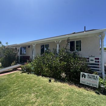 Restore & Construct - New Rain Gutters installed by Restore & Construct. - A single-story residential house with a front garden, a driveway, and a Restore & Construct sign indicating roofing, painting, and window services. - Roofing Near Me - Carson, California